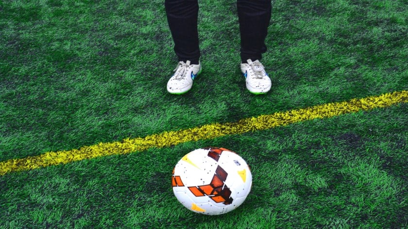 En fotboll och ett par fötter med vita fotbollsskor