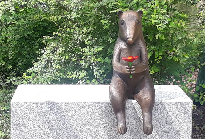 Blomman av Eva Fornåå är en mobil skulptur. En liten figur i sten och brons sitter och håller i en röd blomma