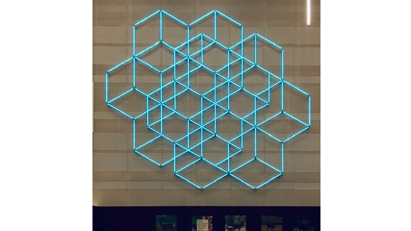 Geometri av Aleksandra Stratimirovic, finns på Nyköpings gymnasium.  Geometri-konstverk i turkos färg sitter på vägg