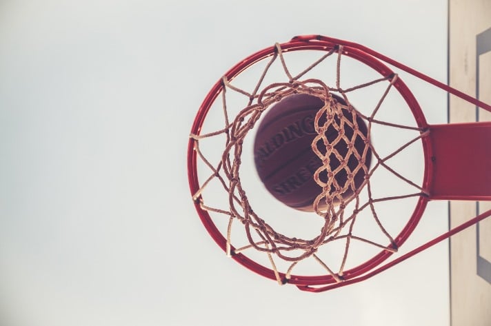 En basketboll på väg ner i nätet i en basketkorg.