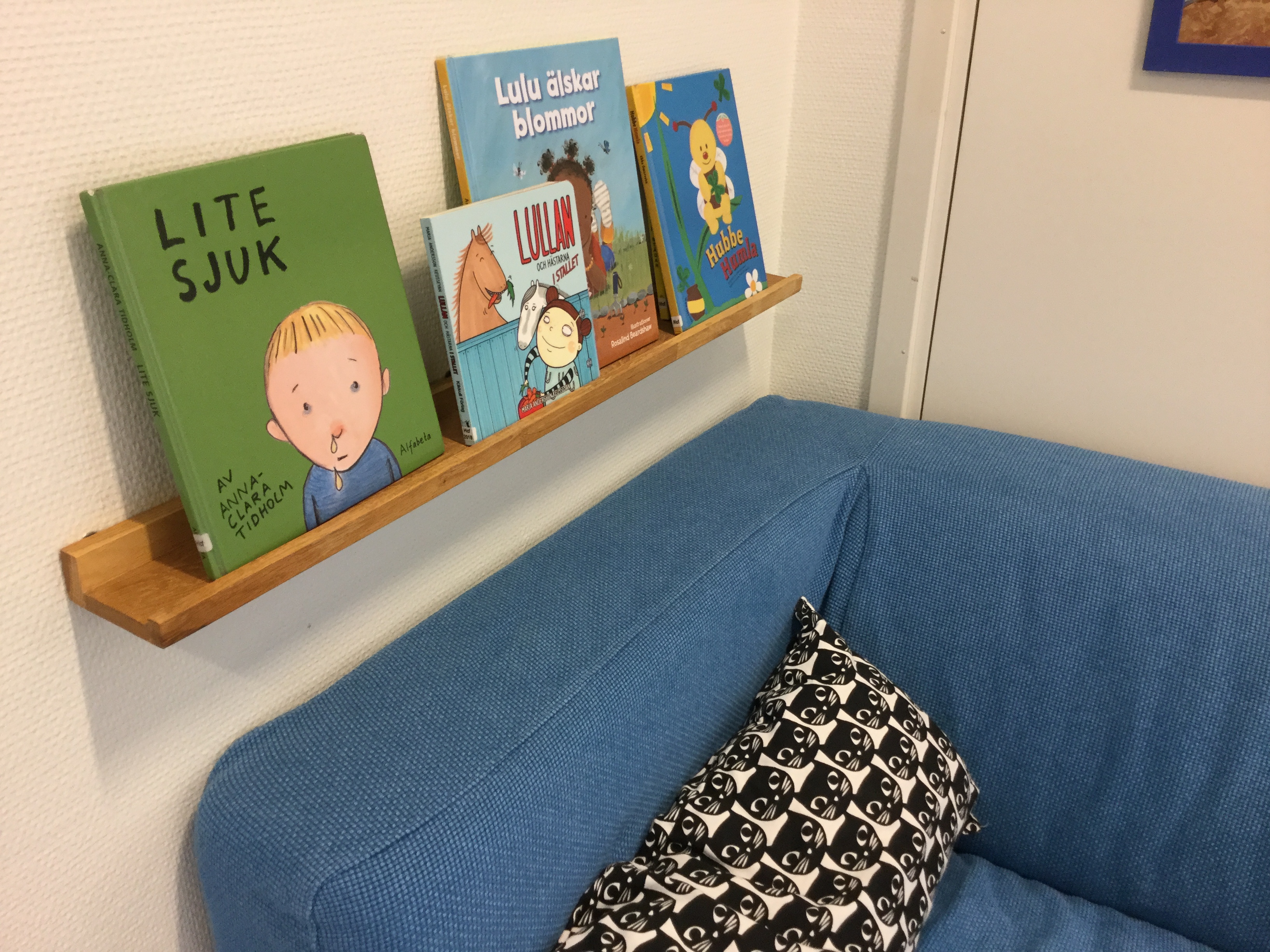 Läshörna med en blå soffa och böcker på en vägghylla.