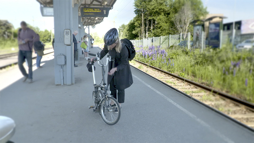 Tjej med cykel på tågperrong, människor passerar förbi Tjej med cykel på tågperrong, människor passerar förbi