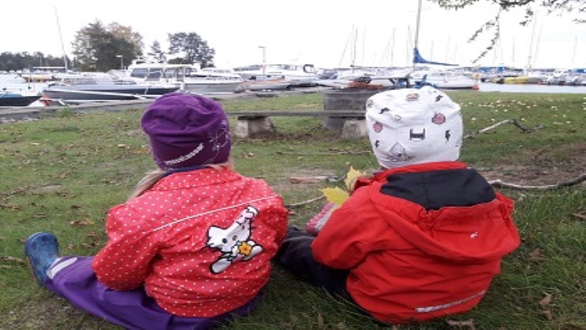Barn sitter vid båtbryggorna