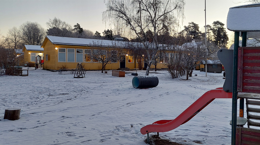 Bild på gården i snötäcke, med rutschkana längst fram 