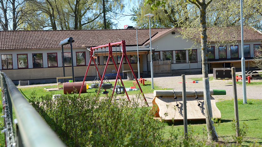 Översiktsbild på del av förskolan gård med gungställning och fasad