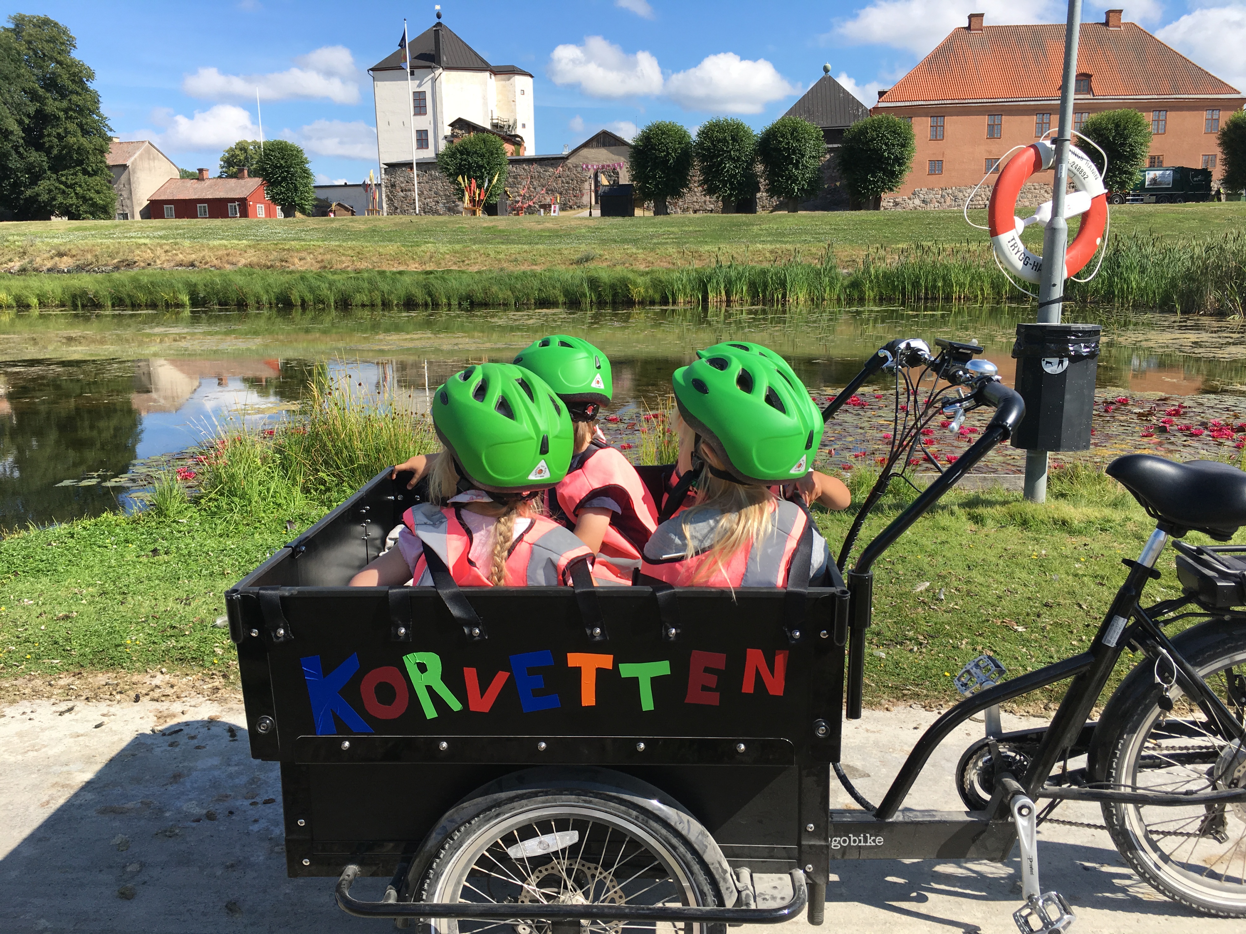 Barn i cargobike framför Nyköpingshus