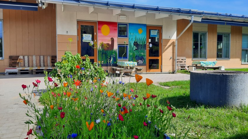 Bild på förskolans gård med blommor i förgrunden