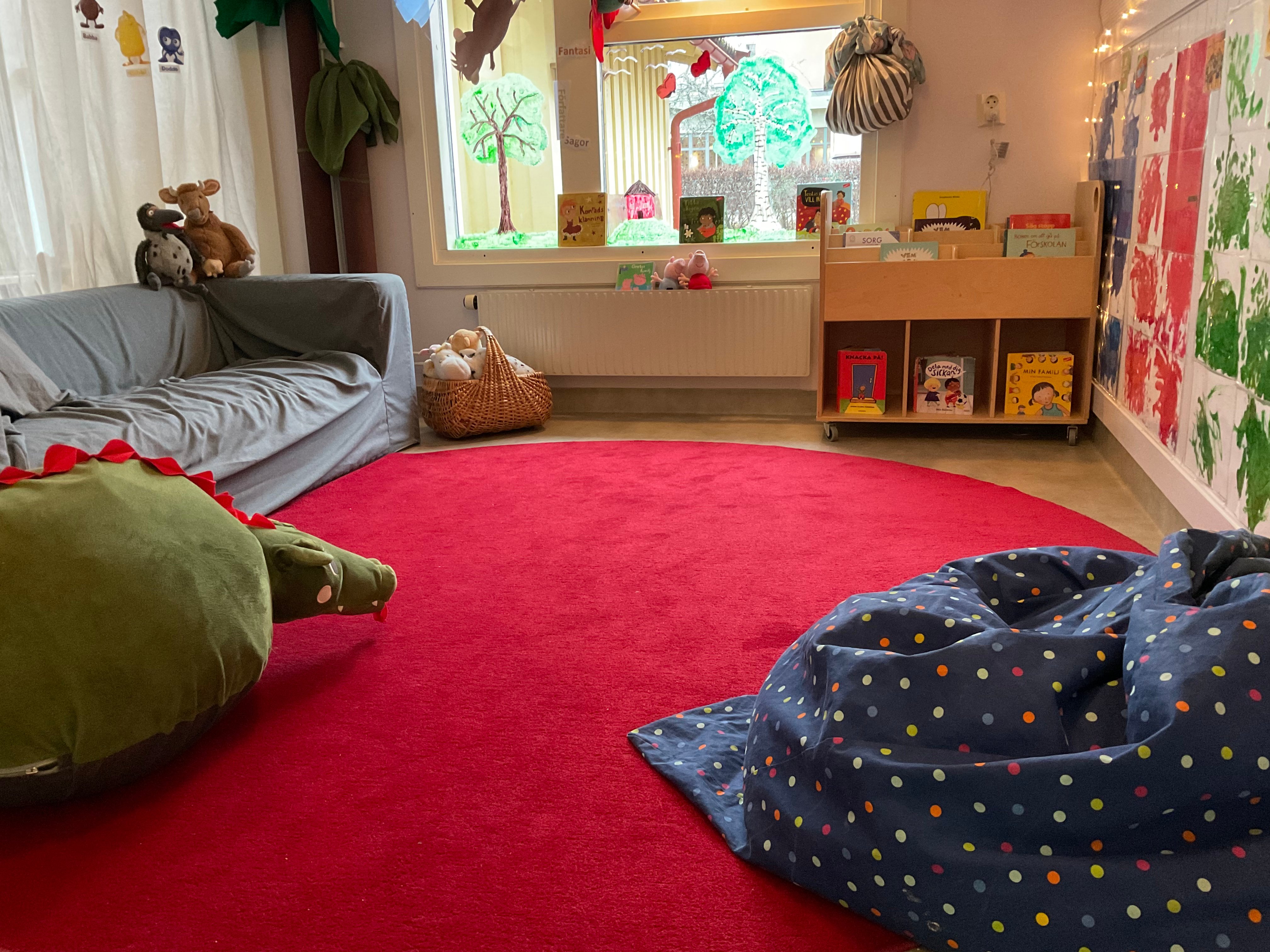 Läsmiljö med sittpuffar och soffa, röd matta på golvet