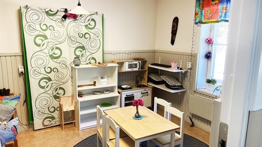 Ett rum på förskolan inrett som ett litet kök med liten spis, mattillbehör och bord och stolar 