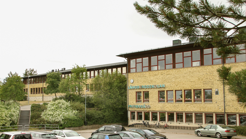 Byggnaden för Gruvans skola Långberg, gul tegelbyggnad, klocka upptill, bruna fönsterkarmar upp till