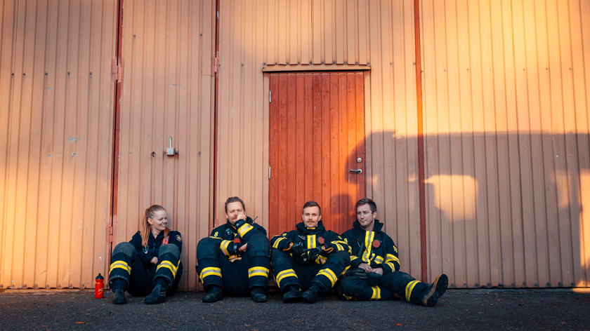 Fyra brandmän sitter och lutar sig mot en vägg