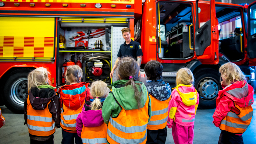 Brandman som utbildar barn framför en brandbil